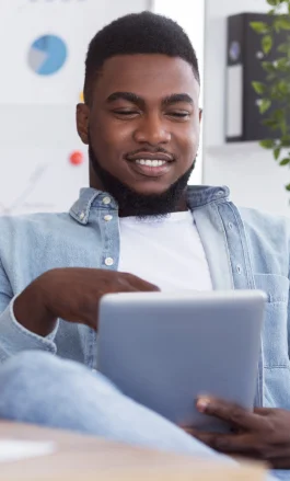 Homem negro, com cabelo curto, barba e bigode, mexendo no tablet.