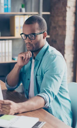 Homem negro, com cabelo curto e óculos, olhando para um papel.